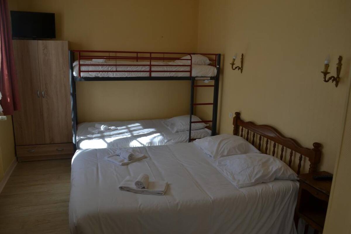 Ein Zimmer mit zwei Etagenbetten, einem Holzschrank und einem Nachttisch mit einer Lampe.