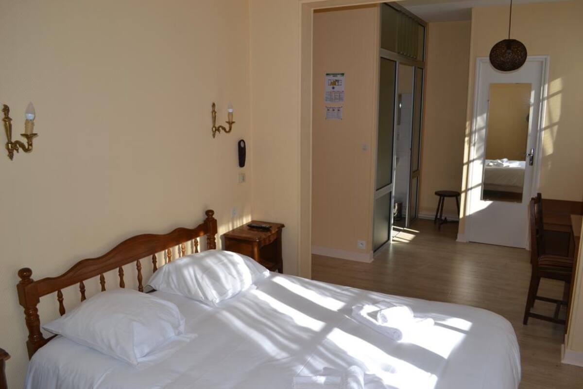 Ein Schlafzimmer mit einem hölzernen Bett, einem Nachttisch, einem Sessel und einem Schreibtisch.