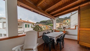 A covered outdoor patio with a table and chairs, overlooking a residential area with terracotta roofs. - Appartamento Clara Vista Mare (Campo nell'Elba)