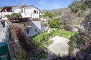 A residential area with a white house, a balcony, and a rocky stream.