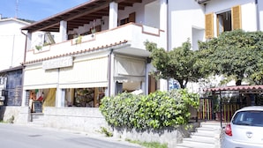 A building with a balcony, a sign that reads "MINIFARIN," and a parked car. - Appartamento Clara Vista Mare (Campo nell'Elba)