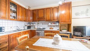 A kitchen with wooden cabinets, a microwave, a dishwasher, and a dining table with chairs. - Appartamento Clara Vista Mare (Campo nell'Elba)