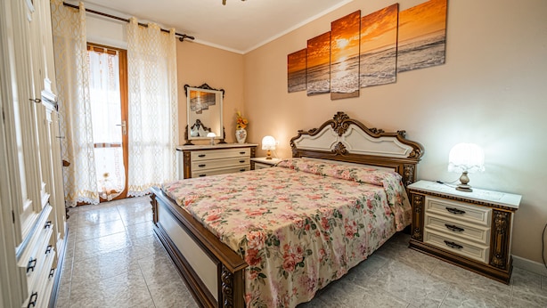 A bedroom with a bed, dresser, nightstand, and a painting on the wall. - Appartamento Clara Vista Mare (Campo nell'Elba)