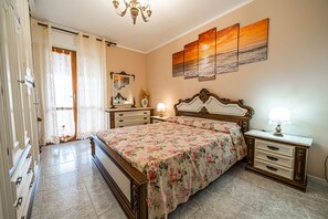 A bedroom with a bed, dresser, nightstand, and a painting on the wall.