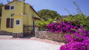 A yellow building with a stone wall and a gate, surrounded by vibrant purple bougainvillea flowers. - Villa Gloria (Portoferraio)