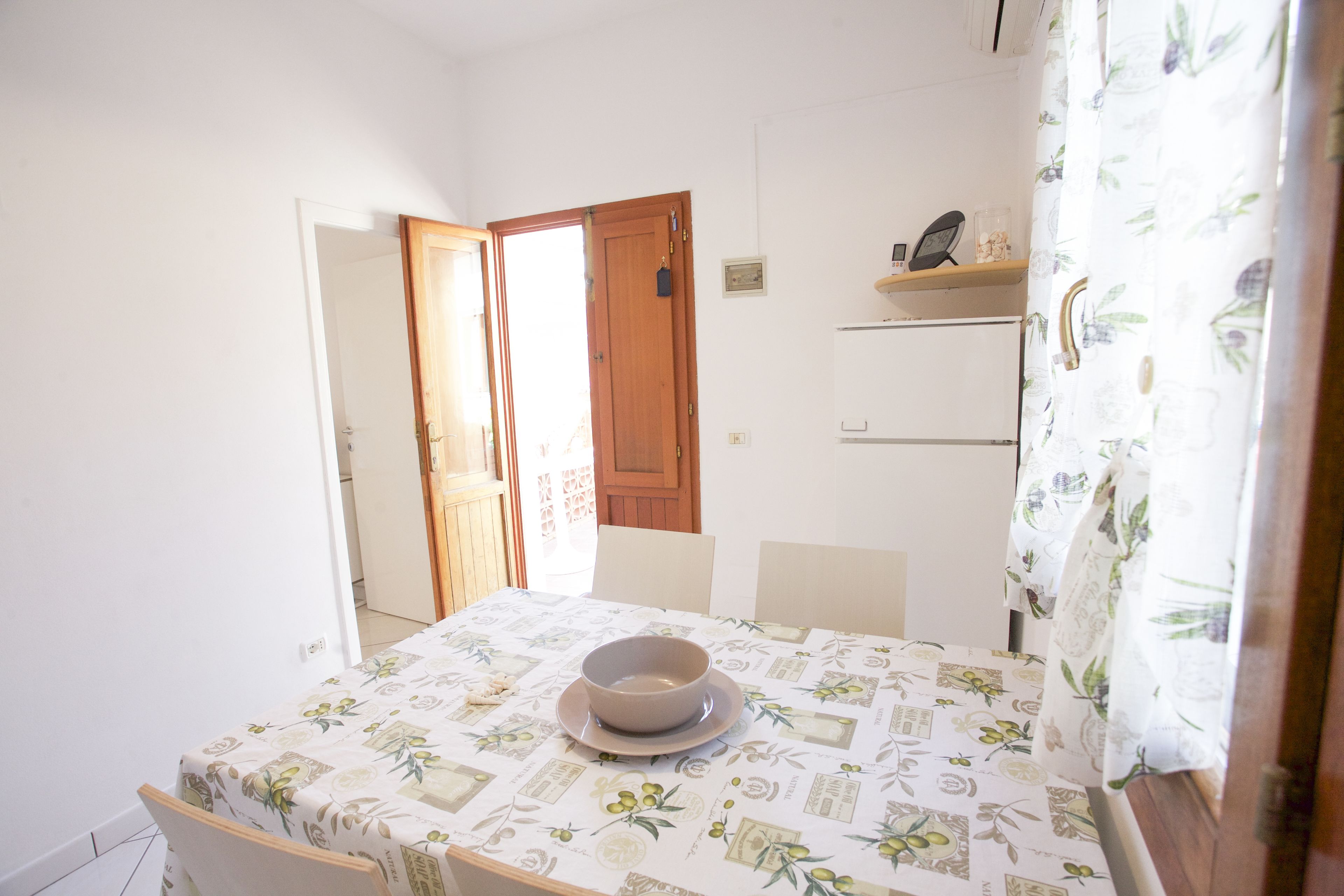 Un'angolare sala da pranzo con un tavolo apparecchiato per due, una ciotola sul tavolo e una porta in legno sullo sfondo.