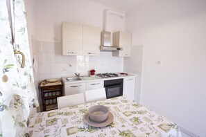 Appartement | Privékitchenette | Een koelkast, een kookplaat, kookgerei, borden en bestek
