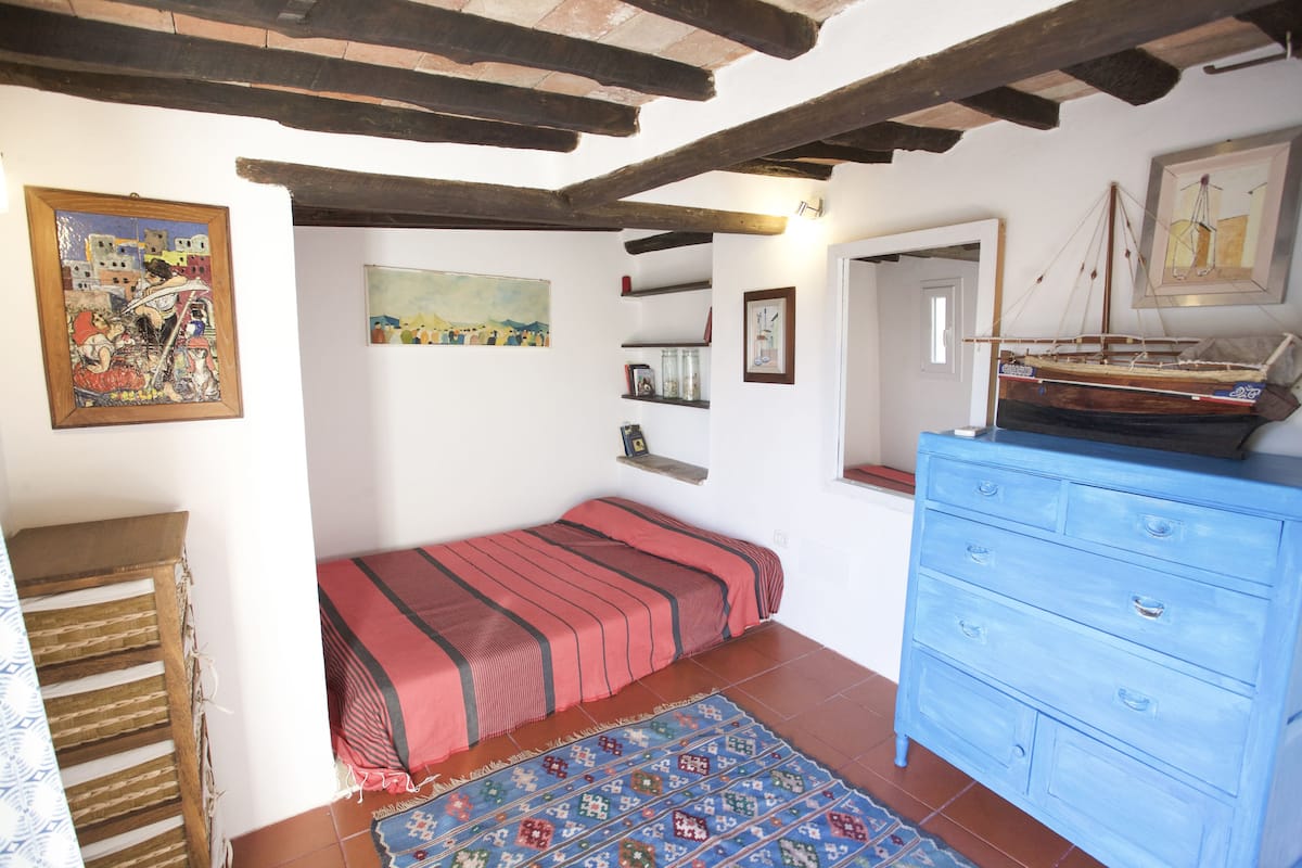 Une chambre à coucher avec un lit, une commode, un tapis et des œuvres d’art accrochées aux murs.