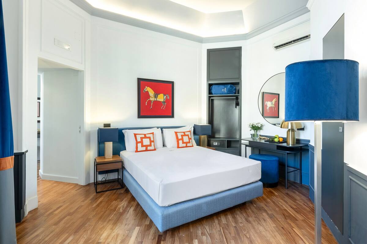 A modern bedroom with a large bed, a desk, and a chair.