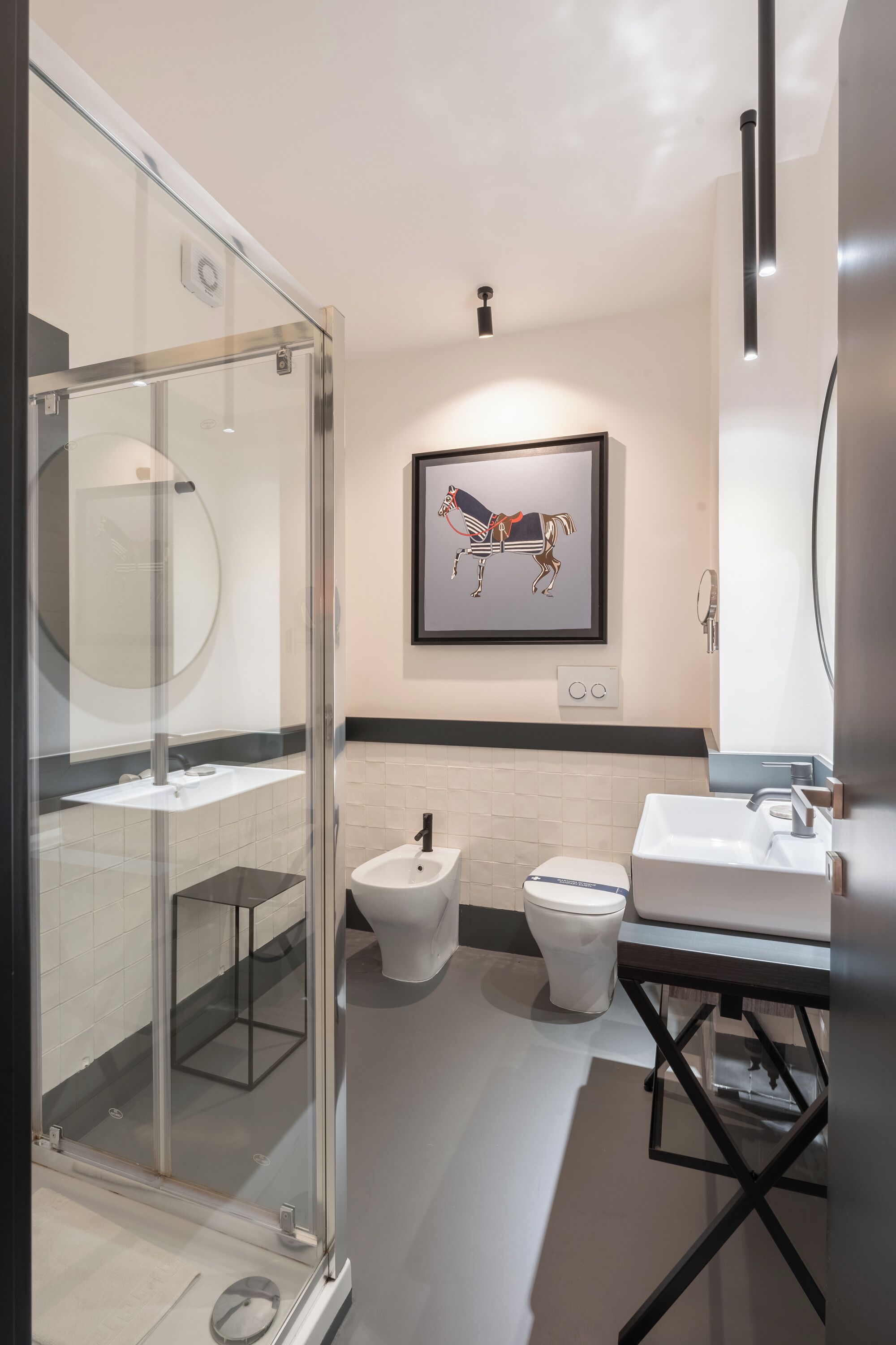 A modern bathroom with a glass shower enclosure, a toilet, bidet, and a sink.