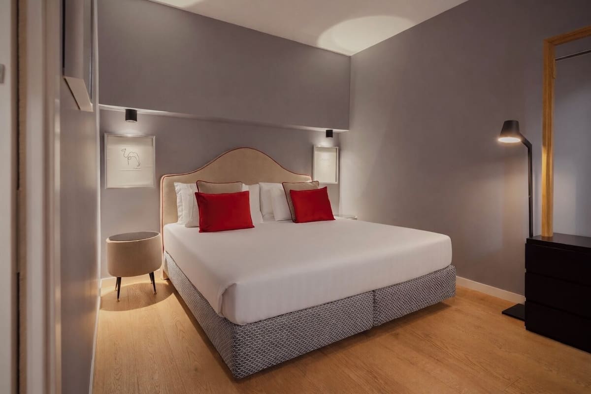 A modern bedroom with a large bed, bedside tables, and a desk.