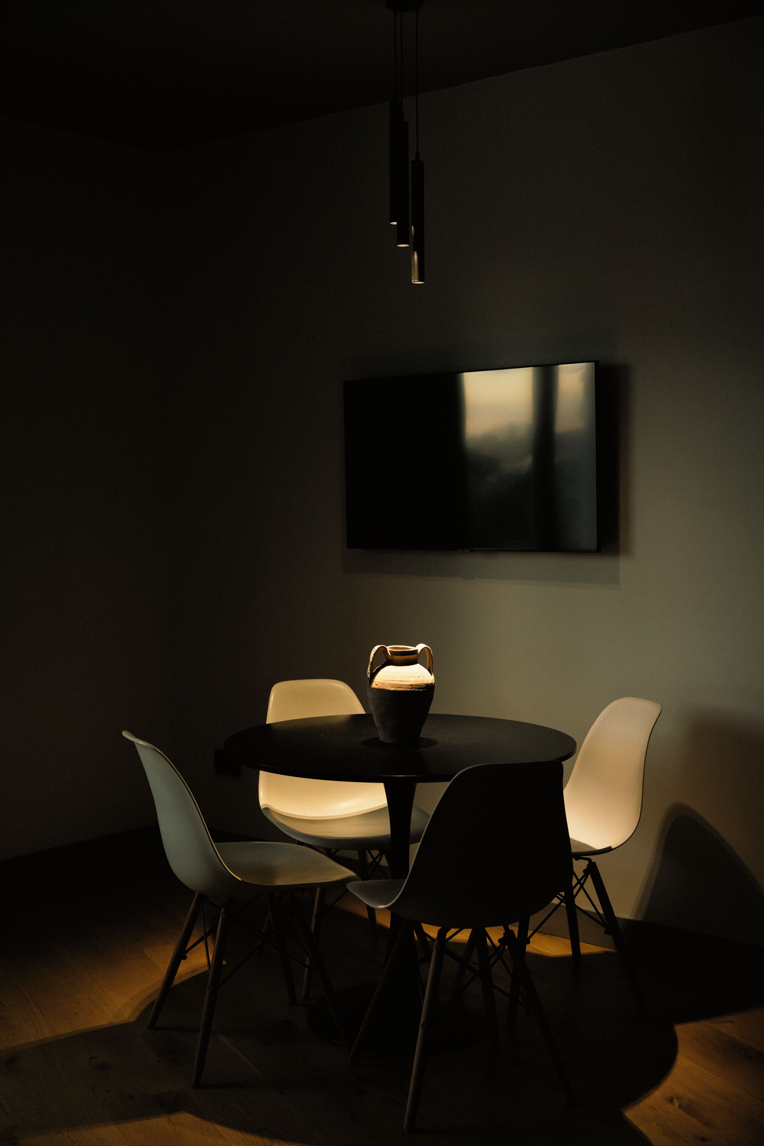 A modern dining area with a round table, four chairs, and a single pendant light.