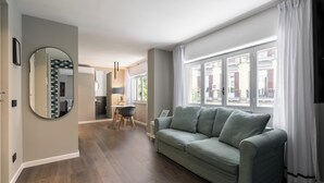 A living room with a sofa, a dining area with a table and chairs, and a large window with curtains. - Le Mummarelle  (Naples)