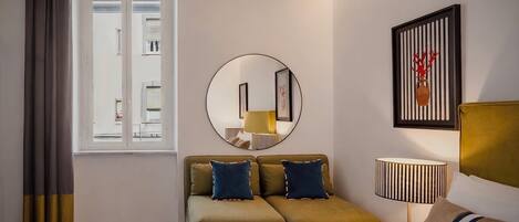 Ein modernes Hotelzimmer mit Bett, einer Couch, einem runden Spiegel, einer Lampe und einem gerahmten Kunstwerk an der Wand.