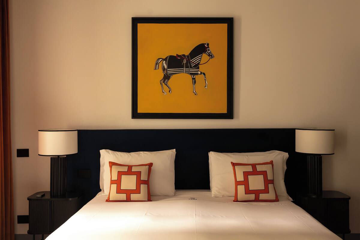 A hotel room with a bed, two nightstands, two lamps, and a framed picture of a horse on the wall.