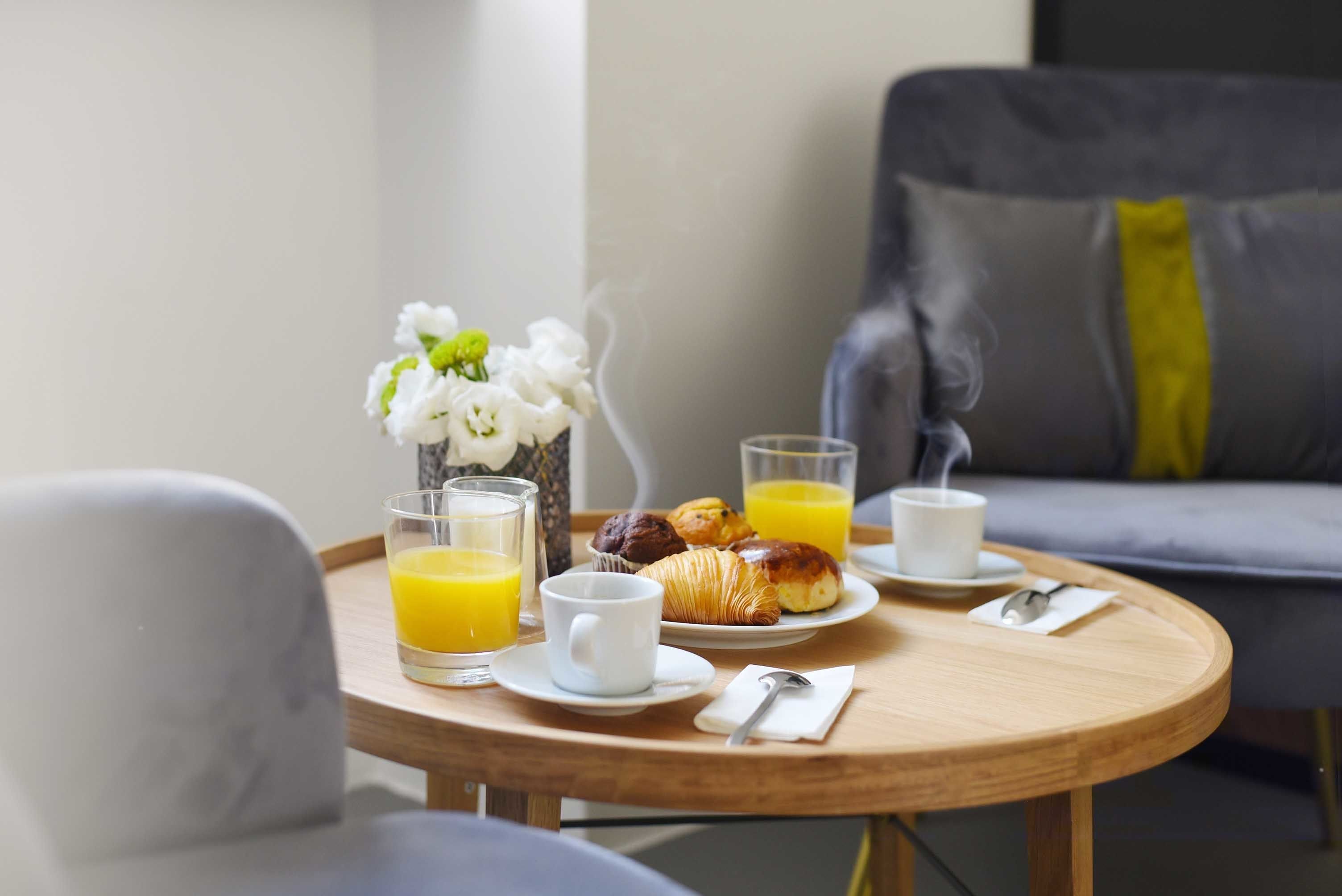 Colazione con croissant, succo d'arancia e una tazza di caffè su un tavolo di legno.