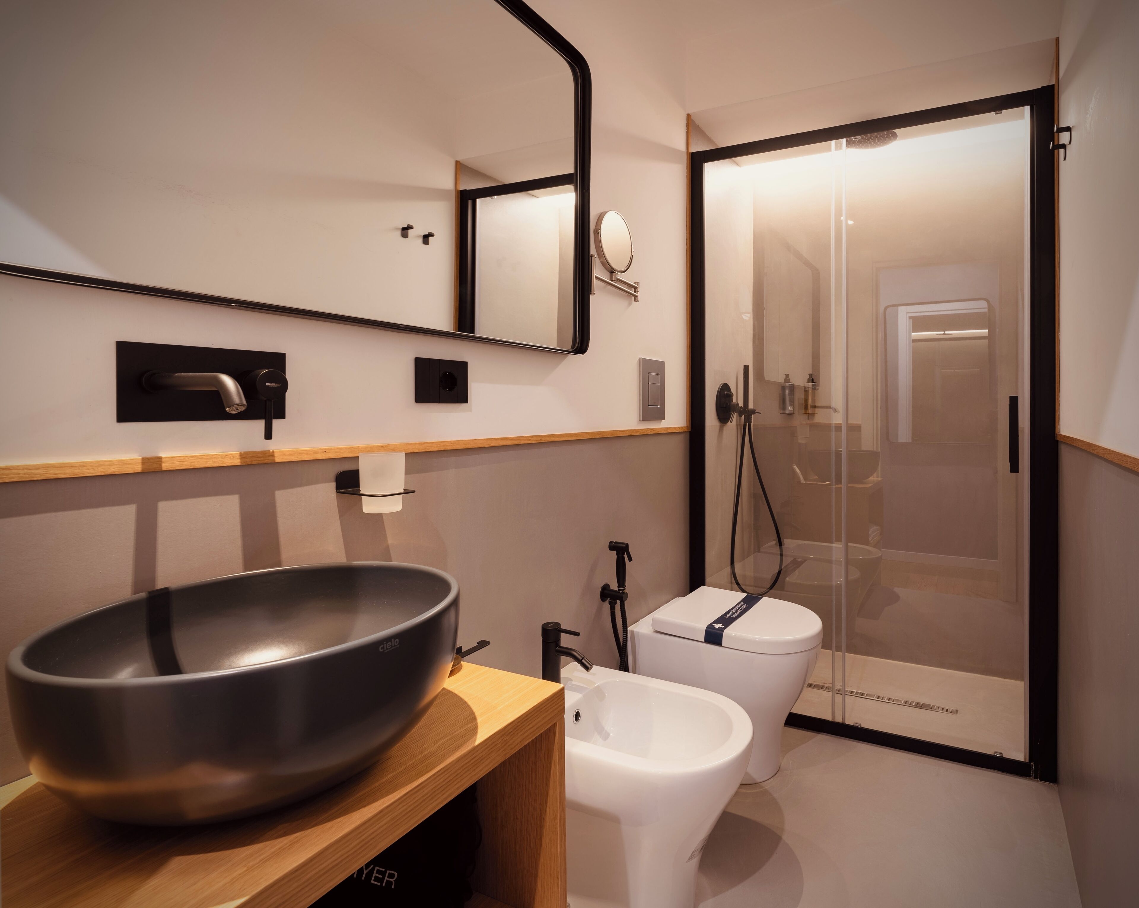 A modern bathroom with a large basin, a toilet, and a shower enclosure.