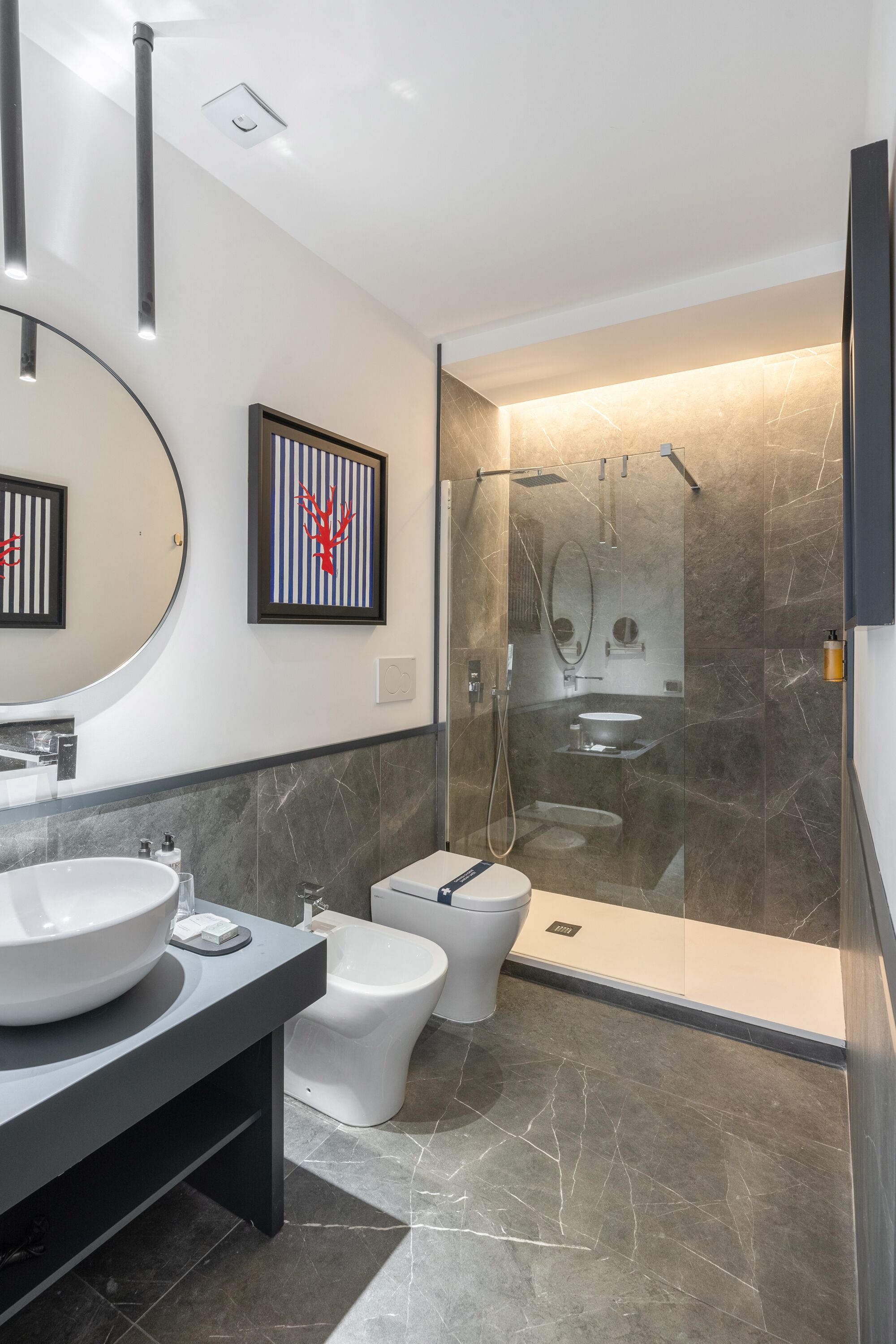 A modern bathroom with a large sink, bidet, and glass-enclosed shower.