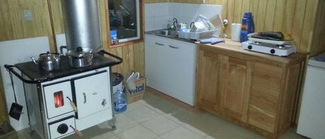 Une cuisine de taille réduite, équipée d’une cuisinière, d’un évier et de meubles de rangement en bois.