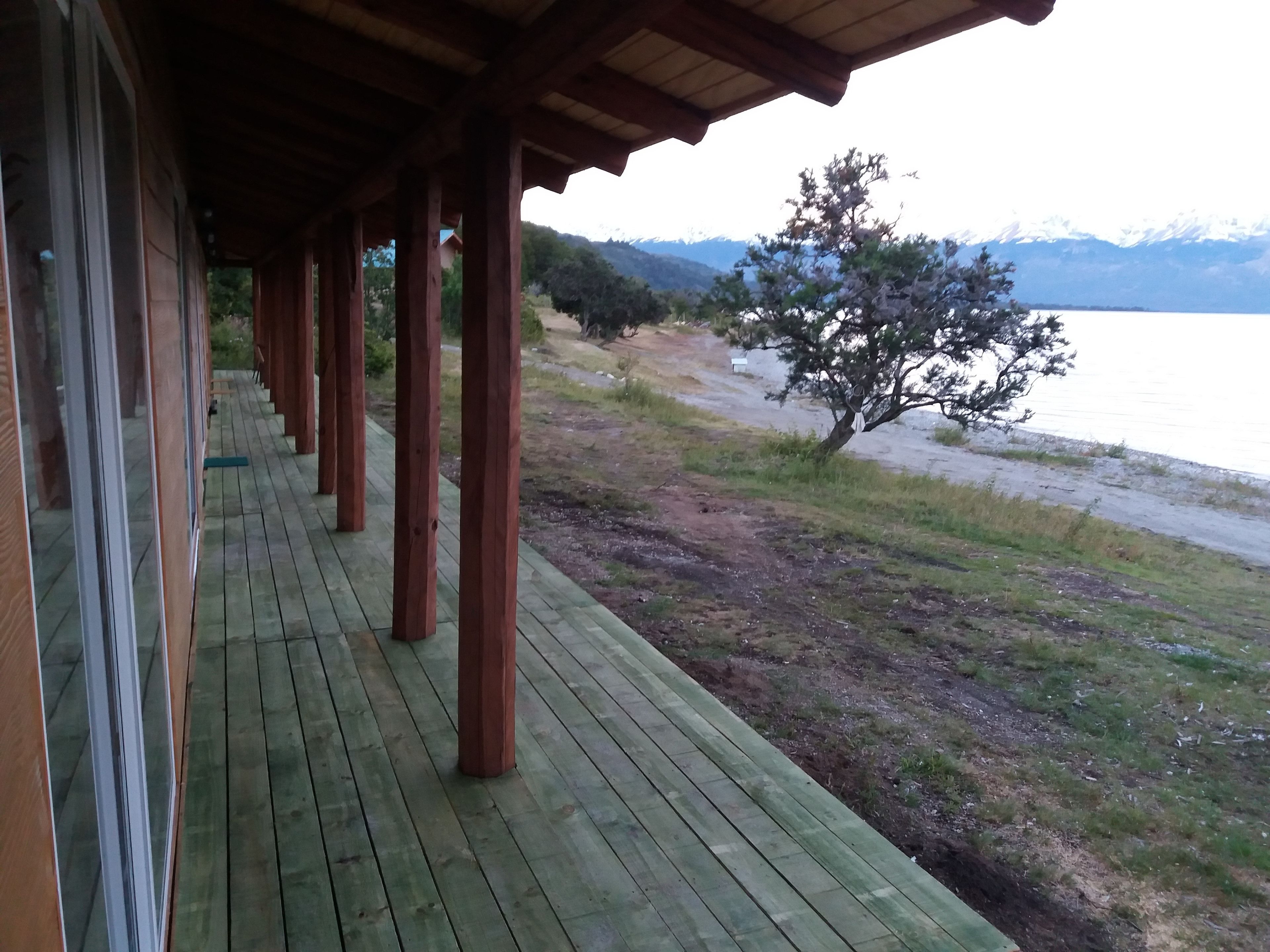 Een houten terras met uitzicht op een meer en bergen.
