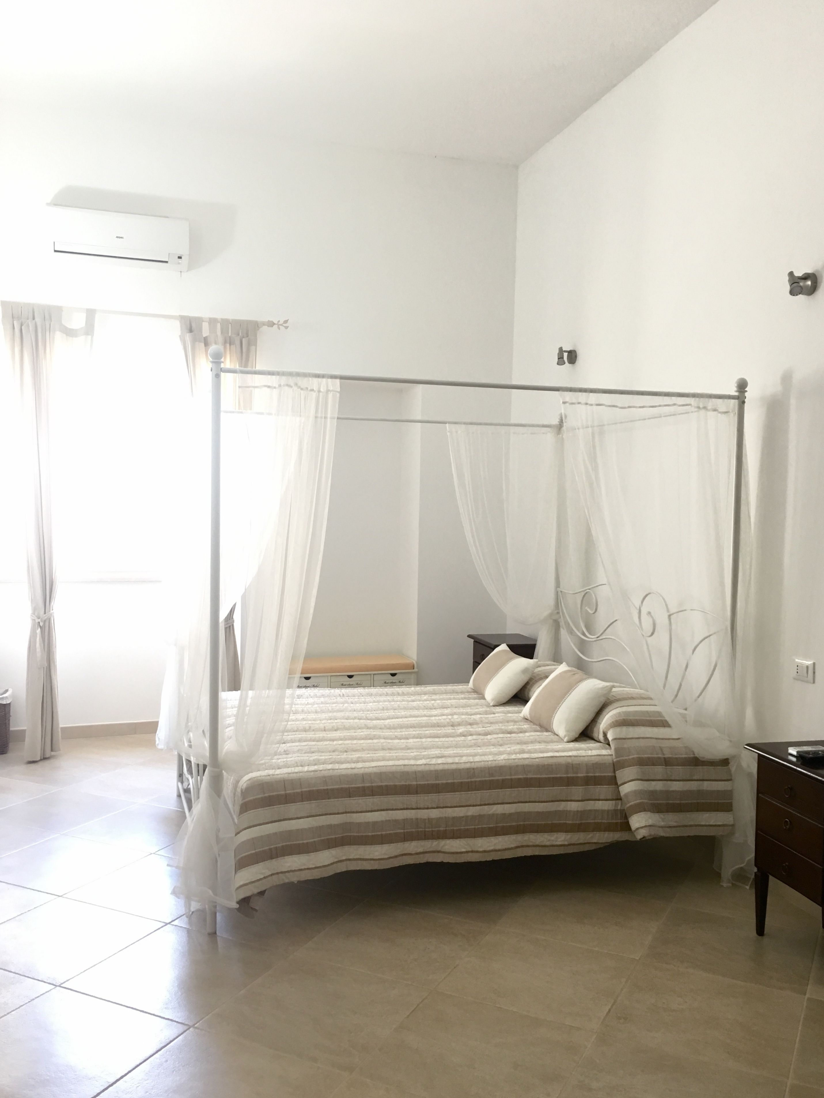 Una cama con dosel, una mesita de noche y una lámpara auxiliar.