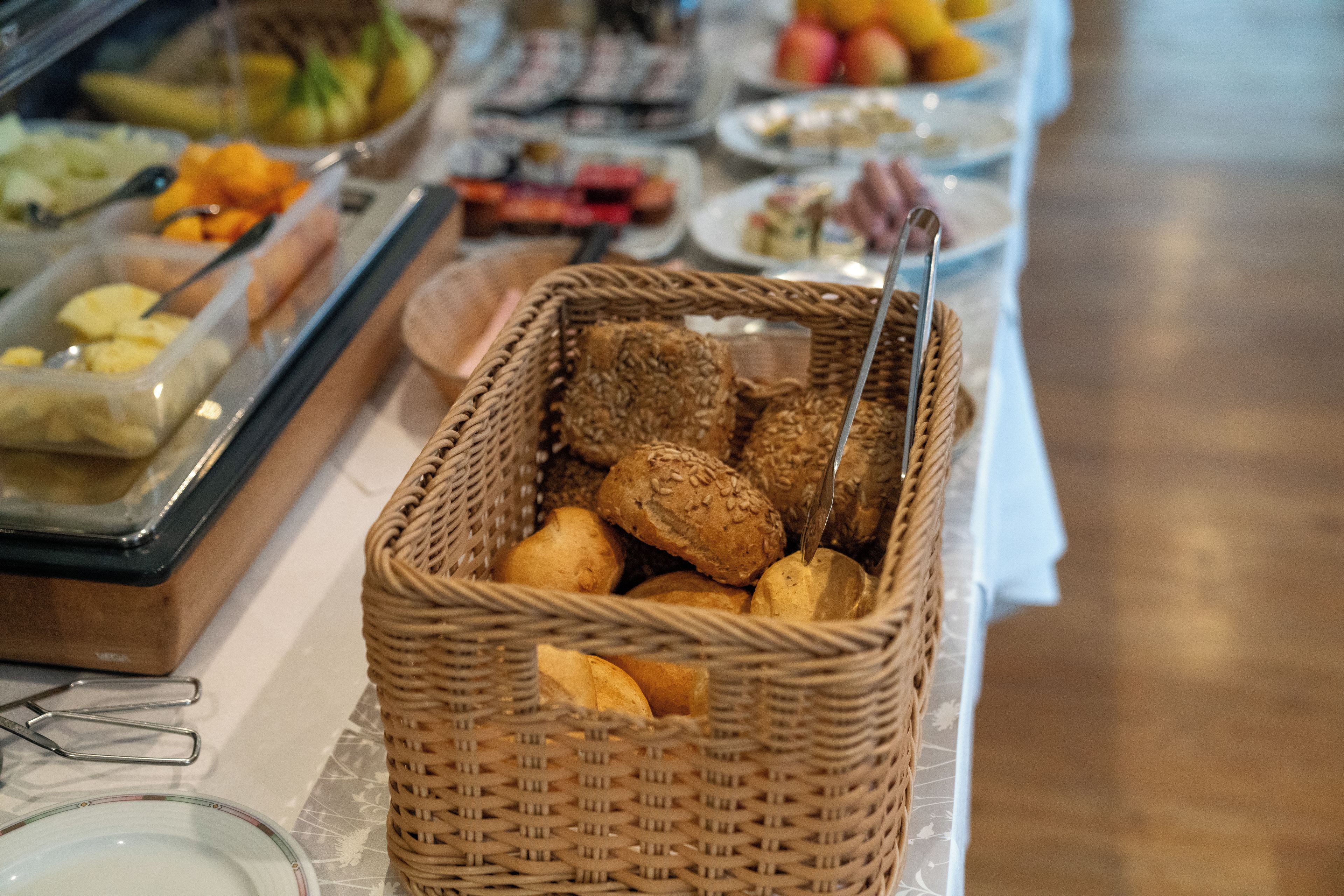 Una mesa de buffet con diversos alimentos, incluyendo panadería y pasteles.
