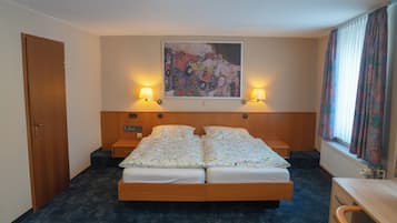 Habitación de hotel con cama doble, dos lámparas de noche, un cuadro en la pared y una ventana con cortinas.