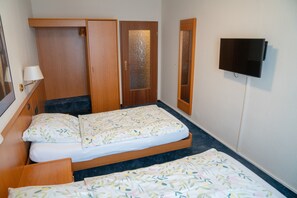 A bedroom with two single beds, a wardrobe, a mirror, and a television on the wall. - Hotel Zum Grafen Hallermunt (Springe)