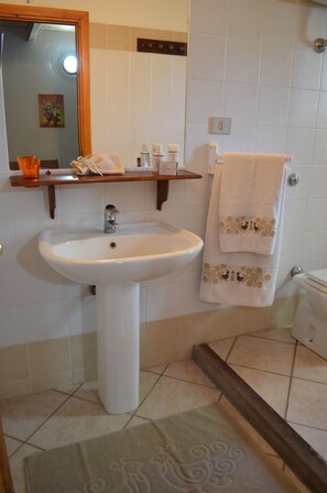 Een badkamer met een wastafel, spiegel, handdoekhouder en toilet.