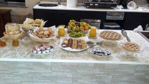 Ein Buffet mit verschiedenen Speisen, darunter Obst, Gebäck und Beilagen.