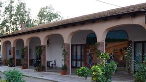 Ein Gebäude mit überdachter Terrasse, Sitzgelegenheiten im Freien und Blumentöpfen.