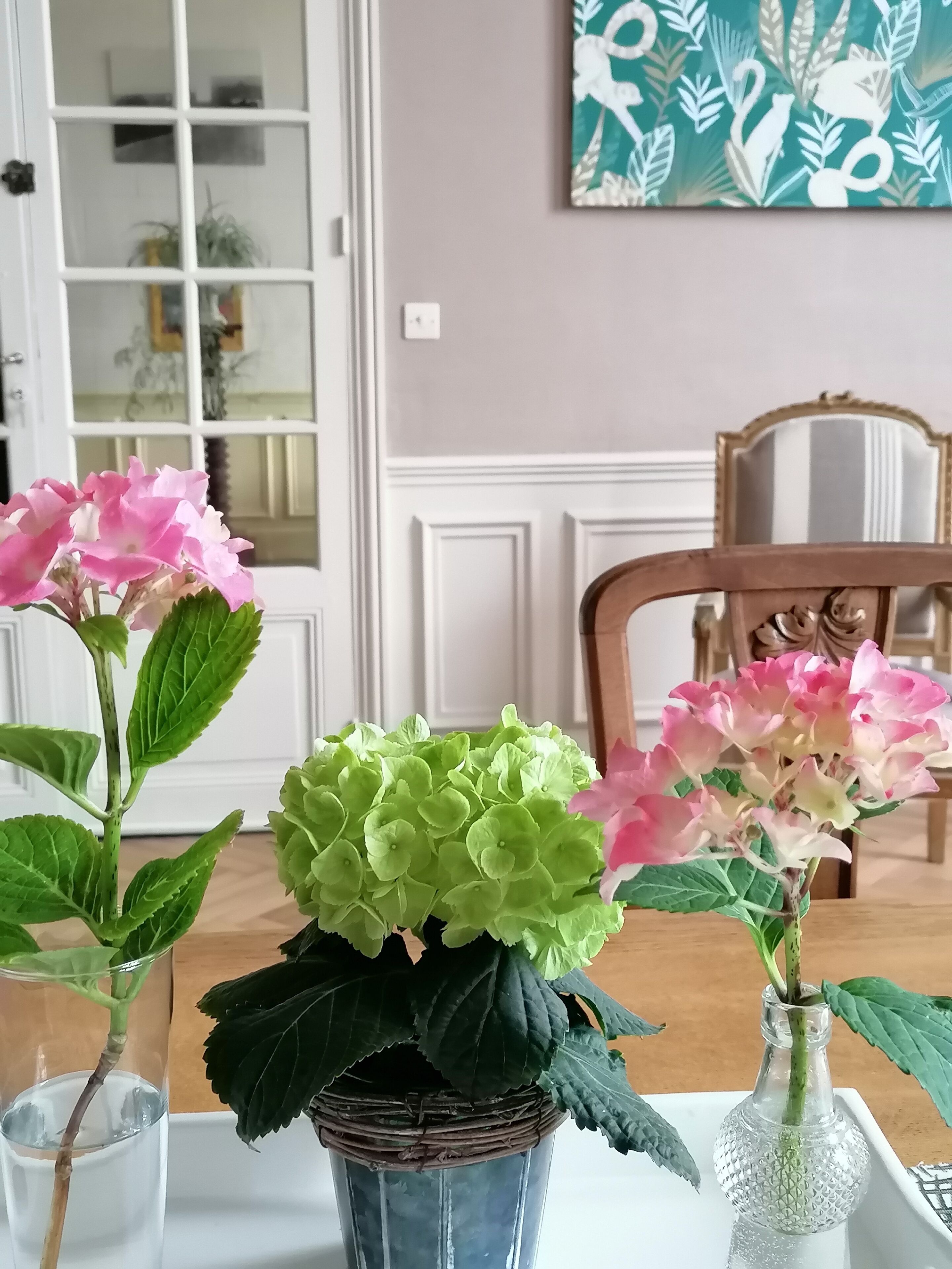 Een eettafel met drie glazen vazen met bloemen.