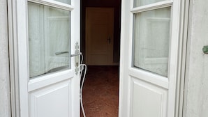 A doorway with a white door and a window, leading to a room with a wooden floor. - II Torchio - Guest House (Dormelletto)