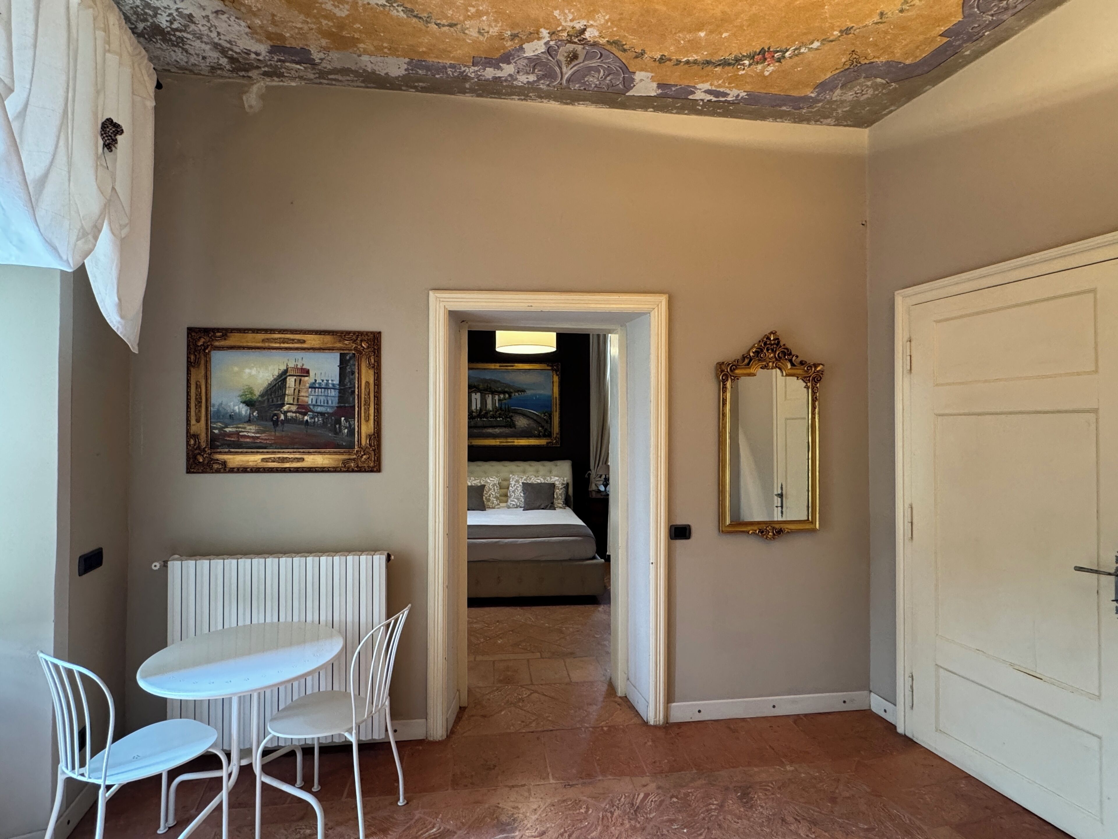 Un couloir comprenant un coin repas, un radiateur, un tableau encadré, un miroir et une porte.