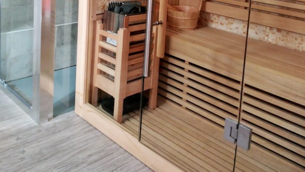Una sauna con bancos de madera y una puerta de cristal, un banco de madera con una toalla, y un banco de madera con una toalla.