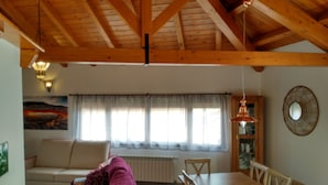 Un salón acogedor con techo de madera, un sofá, una mesa de comedor con sillas y un radiador.