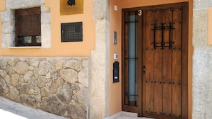Un edificio rústico con un muro de piedra, una puerta de madera con el número 3, y una placa sobre la puerta.