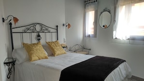 Una cama bien hecha con un cabecero negro, dos almohadas doradas y una colcha blanca.