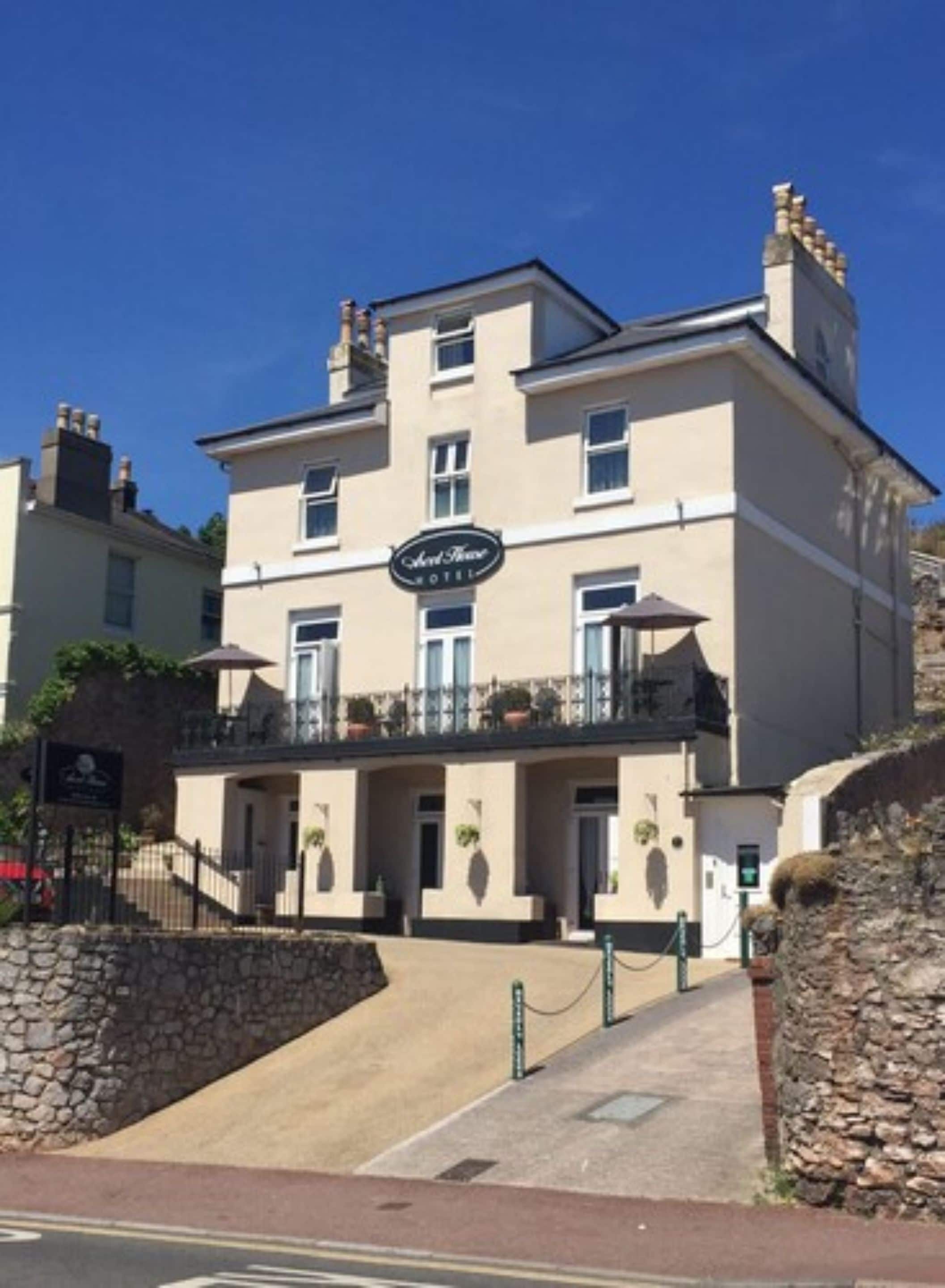 A hotel with a sign reading "Old House Hotel," featuring a traditional facade with multiple windows and a balcony.