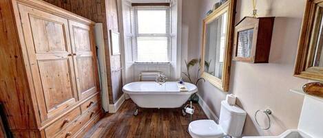 Une salle de bain avec une baignoire sur pieds, des toilettes et un lavabo.