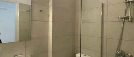 Une salle de bain moderne avec une douche à parois de verre, un lavabo blanc et des toilettes.