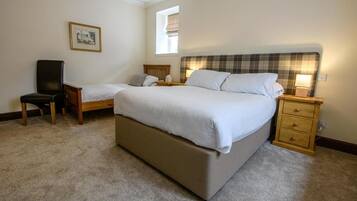 Un dormitorio con dos camas individuales, una silla, una mesita de noche y una mesita auxiliar.