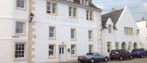 A white building with the sign "The Bridge" and multiple windows.