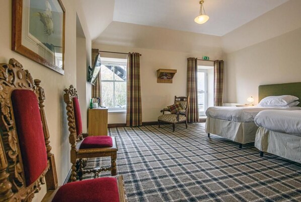 Une chambre d’hôtel avec un tapis à carreaux, deux lits, une chaise et un miroir.