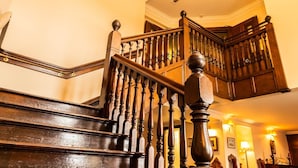 A wooden staircase with a balustrade leading to an upper floor. - The Bridge Guest House (Helmsdale)