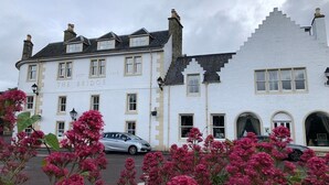 A white building with the sign "The Bridge" and a car parked in front. - The Bridge Guest House (Helmsdale)