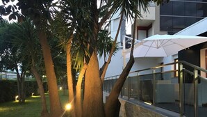 A modern building with a glass facade, outdoor seating area, and trees. - Domus Grand Hotel (Rende)
