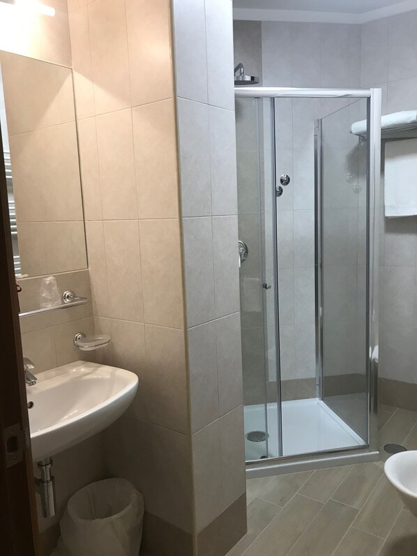 Un baño con ducha envuelta en vidrio, un lavabo e inodoro.