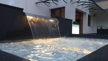 Ein Wasserspiel mit einem stufenartigen Wasserfall in einer modernen Außenanlage.