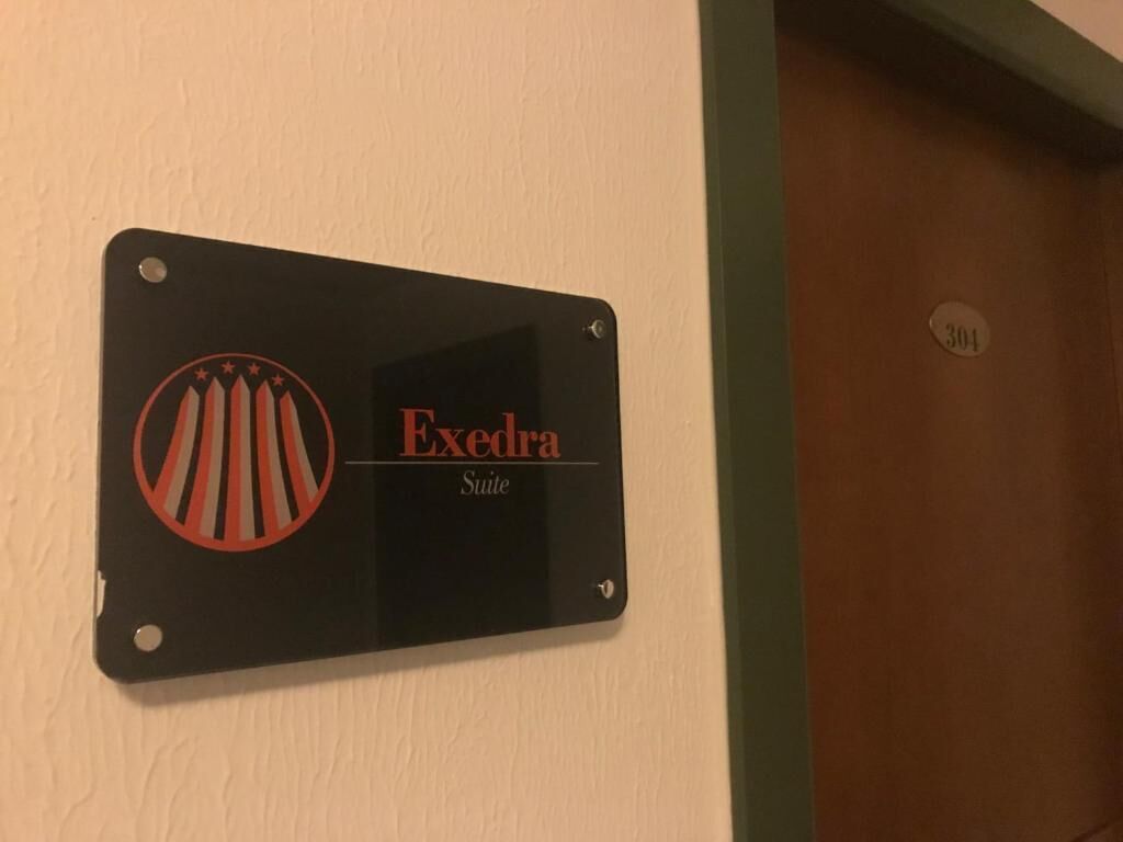 Un panneau noir portant l’inscription « Exedra Suite » et un logo.